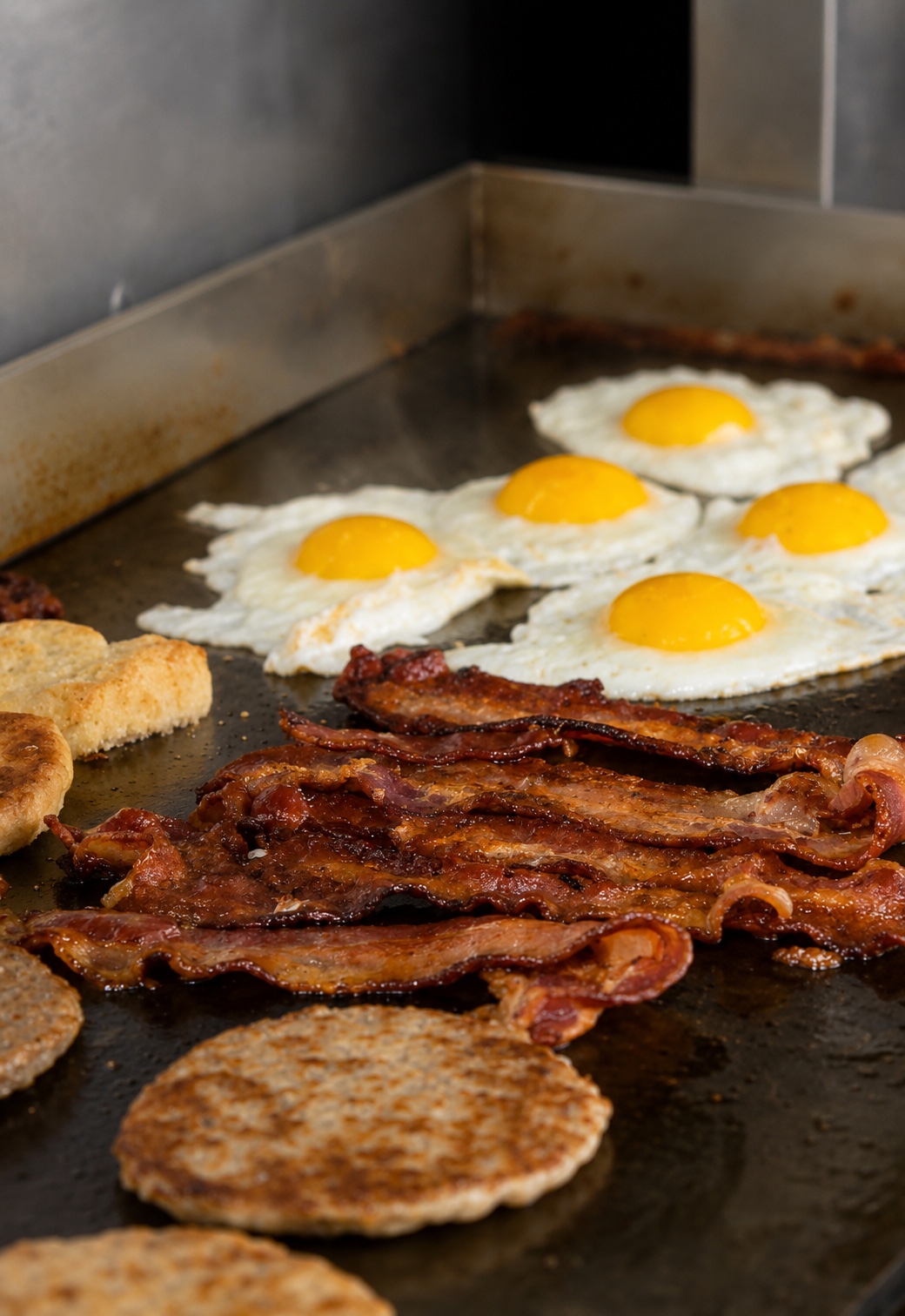 Eggs, bacon and sausage cooking fresh on the griddle